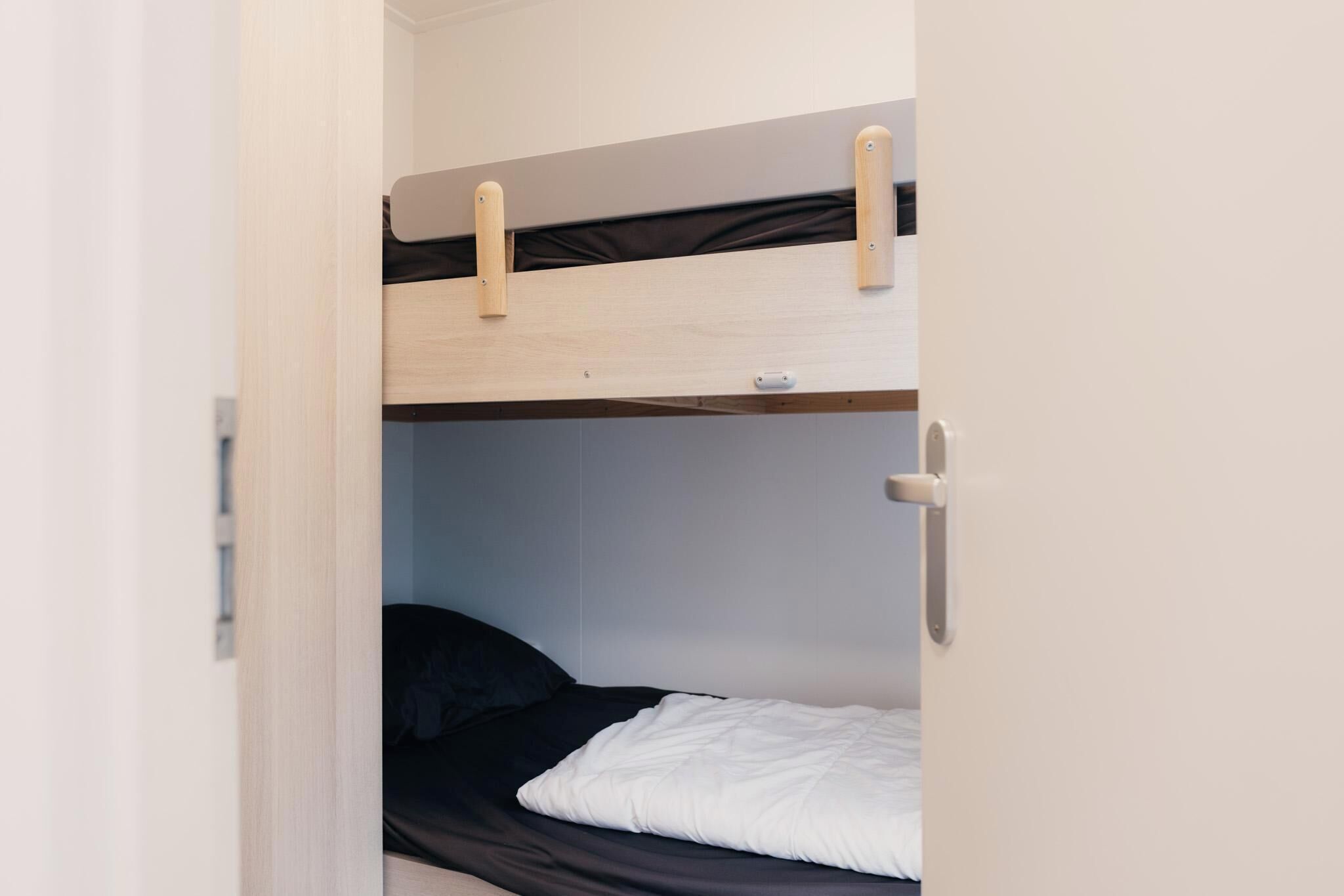 Ein Stockbett mit Holzbalken und einer schwarzen Matratze.