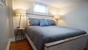 Une chambre à coucher avec un lit, deux lampes de chevet, une petite table et une fenêtre.