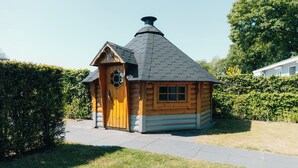 A small log cabin with a steeply pitched roof, a wooden door, and a window.