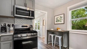 A modern kitchen with stainless steel appliances, a built-in oven, and a window with a view of greenery. - Charming Old Town Bungalow w/ FREE Cruiser Bikes (Fort Collins)