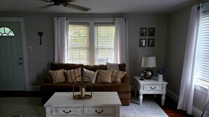 A living room with a brown sofa, white coffee table, and a white side table with a lamp. - Serenity in lancaster county (Paradise)
