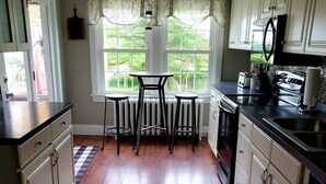 A kitchen with a central island, bar stools, a radiator, and a view of greenery outside. - Serenity in lancaster county (Paradise)