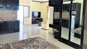 A modern living room with a flat-screen TV, dark wooden cabinets, a patterned rug, and a sliding glass door leading to another room.