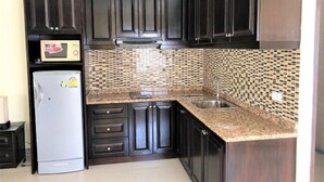 A kitchen with dark wooden cabinets, a stainless steel sink, and a microwave.