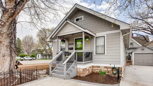 A single-story house with a front porch, a number '305' on the door, and a stone foundation.