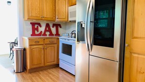 A kitchen with wooden cabinets, a stainless steel refrigerator, a built-in oven, and a stainless steel sink.