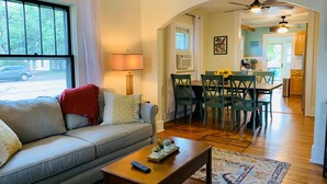 A living room with a sofa, coffee table, and a dining area with chairs and a table.