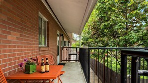 A balcony with a table, chairs, and two beer bottles.