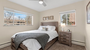 A bedroom with a bed, nightstand, and a ceiling fan.