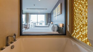 A modern hotel room with a large bathtub, a view of the cityscape through the window, and a decorative wall with geometric patterns.