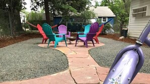 Un espace patio agrémenté de chaises Adirondack aux couleurs vives, d’une petite table et d’une trottinette violette.