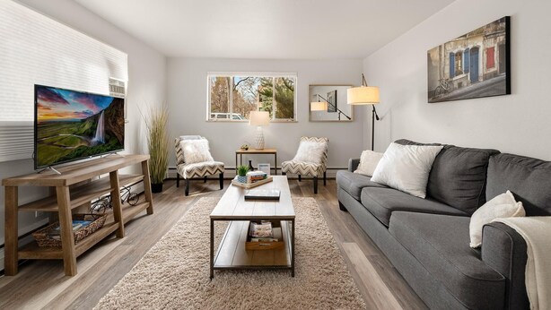 A living room with a flat-screen TV, two armchairs, a sofa, a coffee table, a rug, and a painting on the wall. - Contemporary condo in the heart of Old Town (Fort Collins)