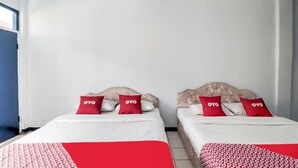 A hotel room with two beds, each with a red and white patterned bedspread and matching pillows. - OYO 3250 Setia Hotel (Cipanas)