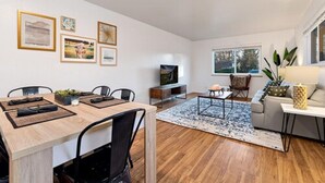 A modern living room with a dining area, a TV, and artwork on the walls.