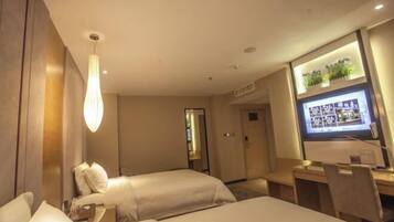 A hotel room with two beds, a desk, a TV, and a large window.