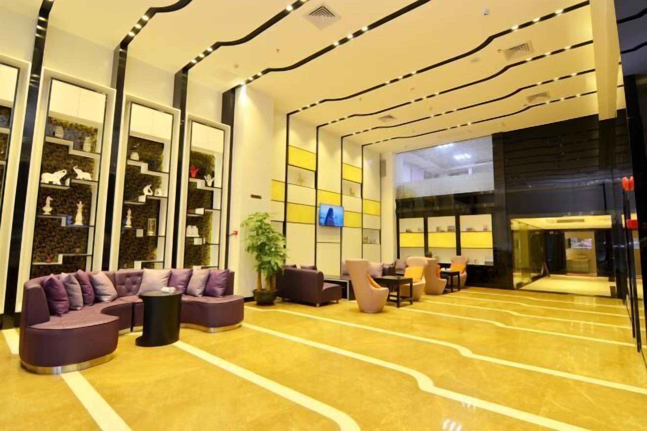 A modern lobby with a curved sofa, armchairs, and a TV screen.