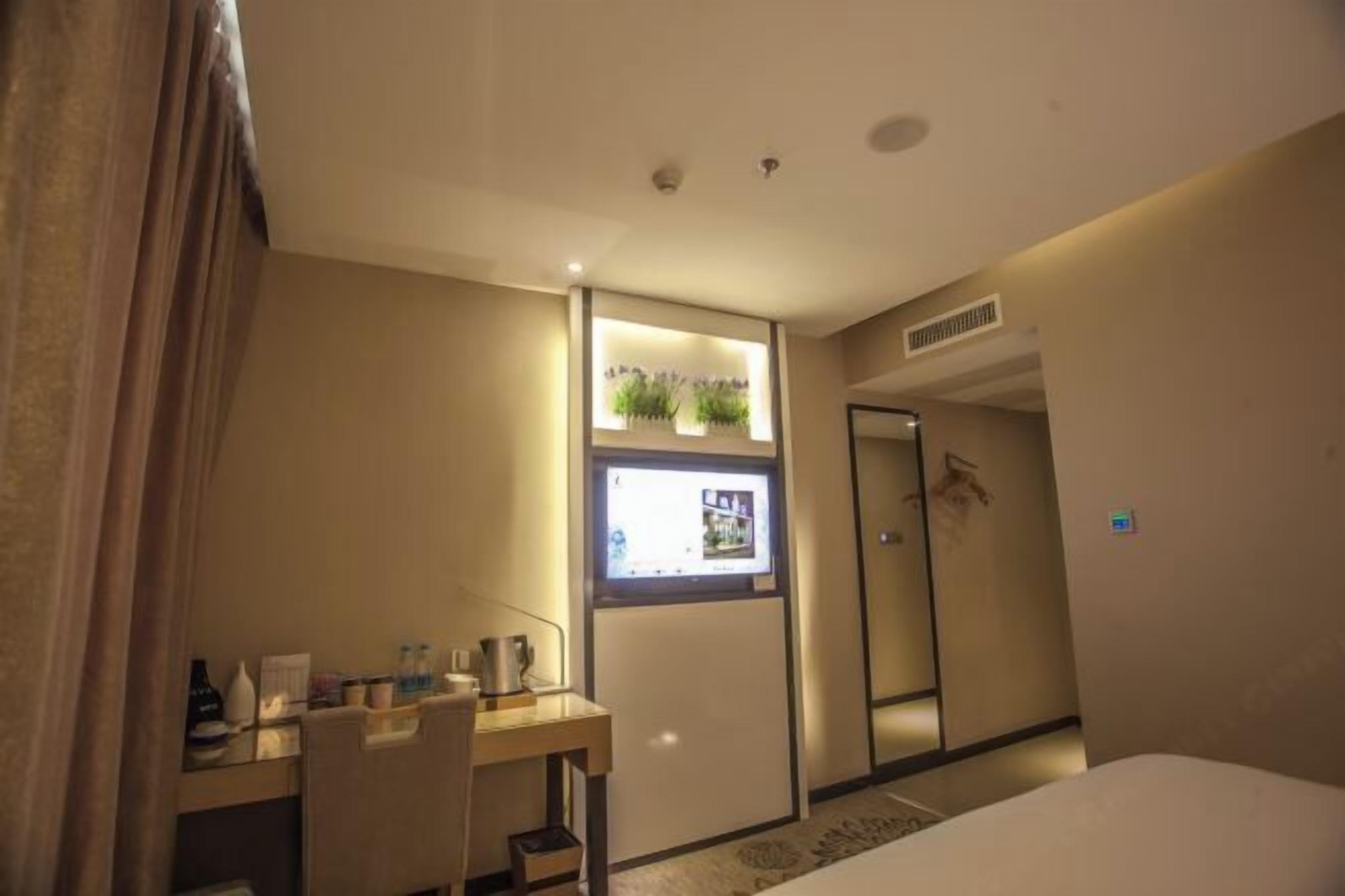 Una habitación de hotel con escritorio, cama, televisor y puerta.