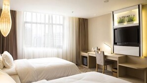 Habitación de hotel con dos camas, un escritorio, un televisor y un ventanal grande.
