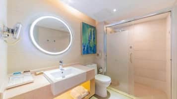 Un baño moderno con un espejo redondo, un lavabo, un inodoro y una ducha con cerramiento de vidrio.