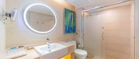 Une salle de bain moderne avec un grand miroir rond, un lavabo, des toilettes et une douche à parois de verre.