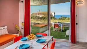 A dining area with a table set for four, red chairs, and a view of the sea through large glass doors. - Apt Mari E Monti A 2 Km Da Riserva Dello Zingaro (Castellammare del Golfo)