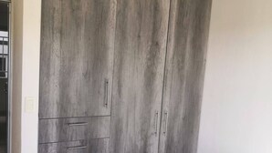 A bedroom with a large wardrobe, a bed, and a tiled floor. - Cozy Apartment in the City of Morelia (Morelia)