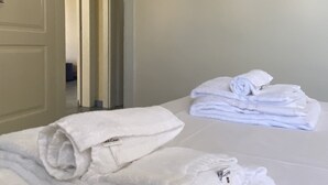 A hotel room with a neatly made bed, a stack of towels, and a framed photo on the wall. - Villetta Sole (Gallipoli)