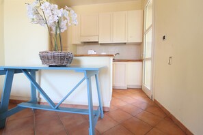 A kitchen with white cabinets, a blue table, and a wicker basket with flowers.