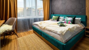 Una camera d'albergo moderna con un letto grande, una poltrona, vista sulla città e un motivo geometrico sul muro.