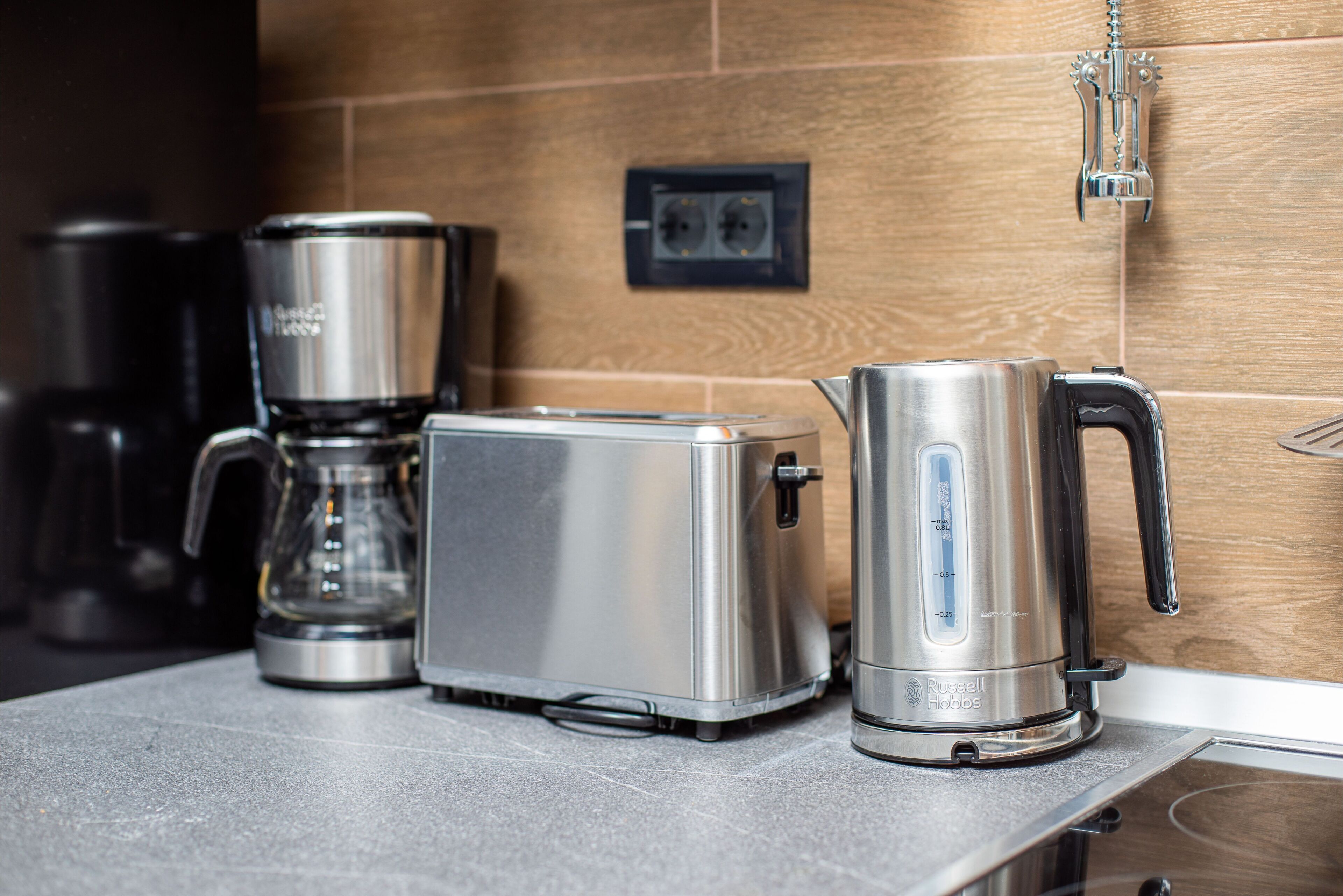 A kitchen with a toaster, a coffee maker, and a kettle on a countertop.