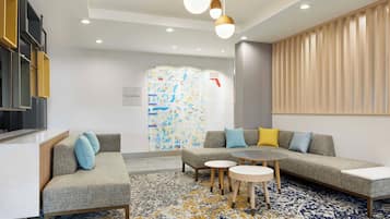 Un moderno vestíbulo de hotel con un sofá modular, una mesa redonda y un mapa en la pared.