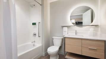 Un baño moderno con bañera, inodoro y tocador con espejo.