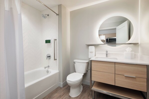 A modern bathroom with a bathtub, toilet, and vanity with a mirror.