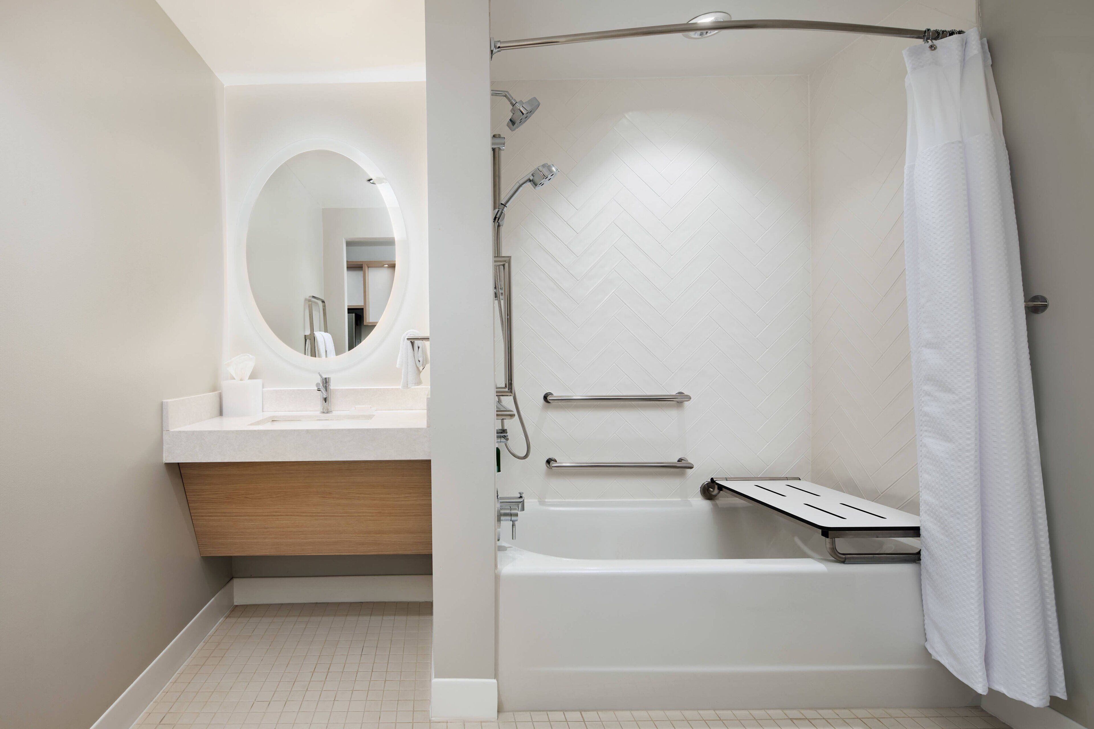 Un baño moderno con bañera, ducha, tocador con espejo y un perchero para toallas.