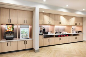 Una cocina moderna con armarios de madera, dispensador de bebidas y un refrigerador.