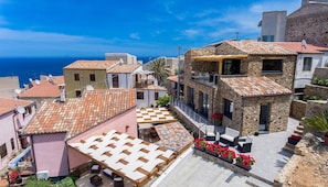 A coastal town with stone buildings, a terrace with outdoor seating, and a view of the sea.