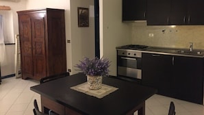 A kitchen with dark cabinets, a stove, and a dining table with a vase of flowers. - PRETTY AND VERY CENTRAL ATTIC ONE STEP FROM THE SEA (Varazze)