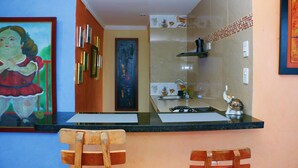 A kitchen with a marble backsplash, wooden chairs, and a painting on the wall. - Sea View Apartment 1-11c air Wifi (Cartagena)