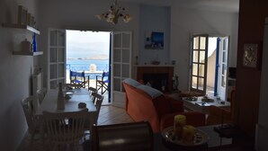 A spacious living area with a dining table, chairs, a sofa, and a fireplace. - Villa Iokasti Sea View (Corinth)