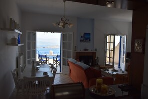 A spacious living area with a dining table, chairs, a sofa, and a fireplace. - Villa Iokasti Sea View (Corinth)