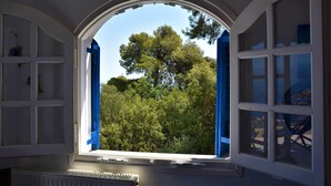 A room with a large arched window, a radiator below, and a view of trees outside. - Villa Iokasti Sea View (Corinth)