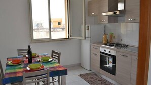A compact kitchen with a dining area, featuring a window, a stove, and a refrigerator. - Charming Holiday Home Near The Beach With A Terrace, Pets (Melendugno)
