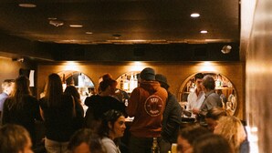 A crowded bar with people sitting and standing around tables. - Broken Hill Designer Baker St Flat Mountain View.  (Nelson)