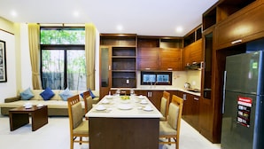 Una cocina moderna con armarios de madera, una mesa de comedor para cuatro personas y un horno empotrado.