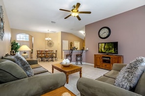 A living room with a sofa, coffee table, TV, and a ceiling fan. - 3 Bedroom Budget Home - Private Pool (Davenport)