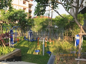 A playground with exercise equipment, surrounded by greenery and residential buildings. - 3008 - 1 Bedroom Seaview Apartment, Unixx Pattaya (Pattaya)