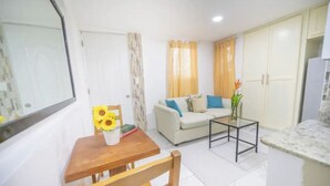 A modern living room with a white sofa, a wooden dining table, and a glass coffee table. - 2 Guests 1bed Studio 3min To Beach And Main Street (Sosúa)