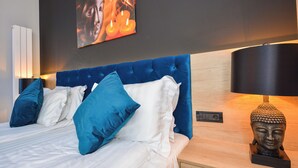 Une chambre à coucher moderne avec une tête de lit capitonnée, une statue de Bouddha et un tableau accroché au mur.