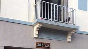 A building with a wooden door, a balcony with metal railings, and a sign above the door. - Loft In Merida For Five (Mérida)