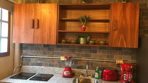 A kitchen with granite countertops, wooden cabinets, a built-in oven, a sink, a red toaster, and a coffee maker. - Loft In Merida For Five (Mérida)